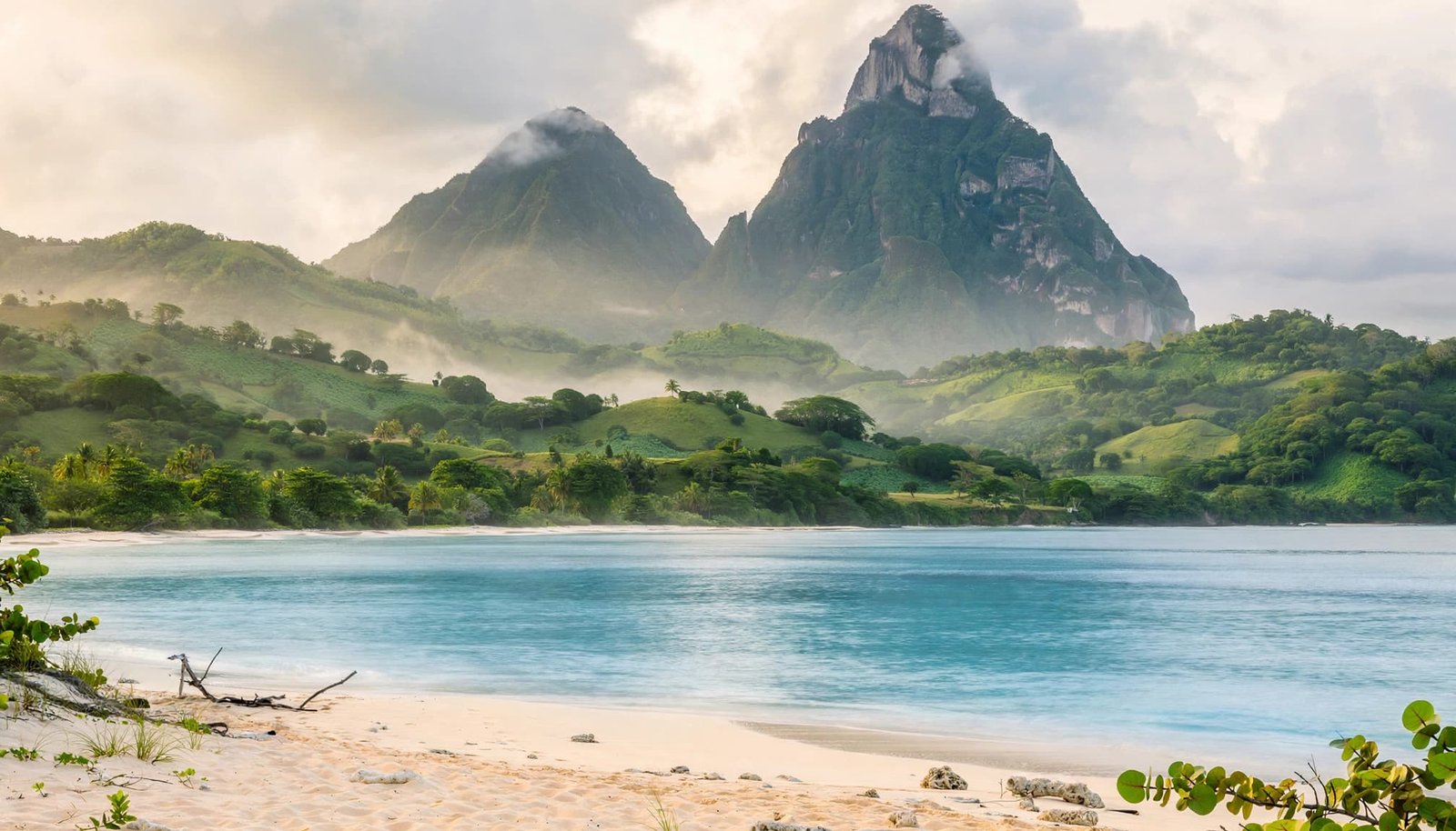 A pale beach and turquoise sea sit below green hills and Saint Lucia's twin Pitons.