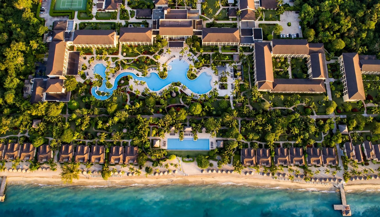 A beachfront resort has two pools divided by tropical gardens.
