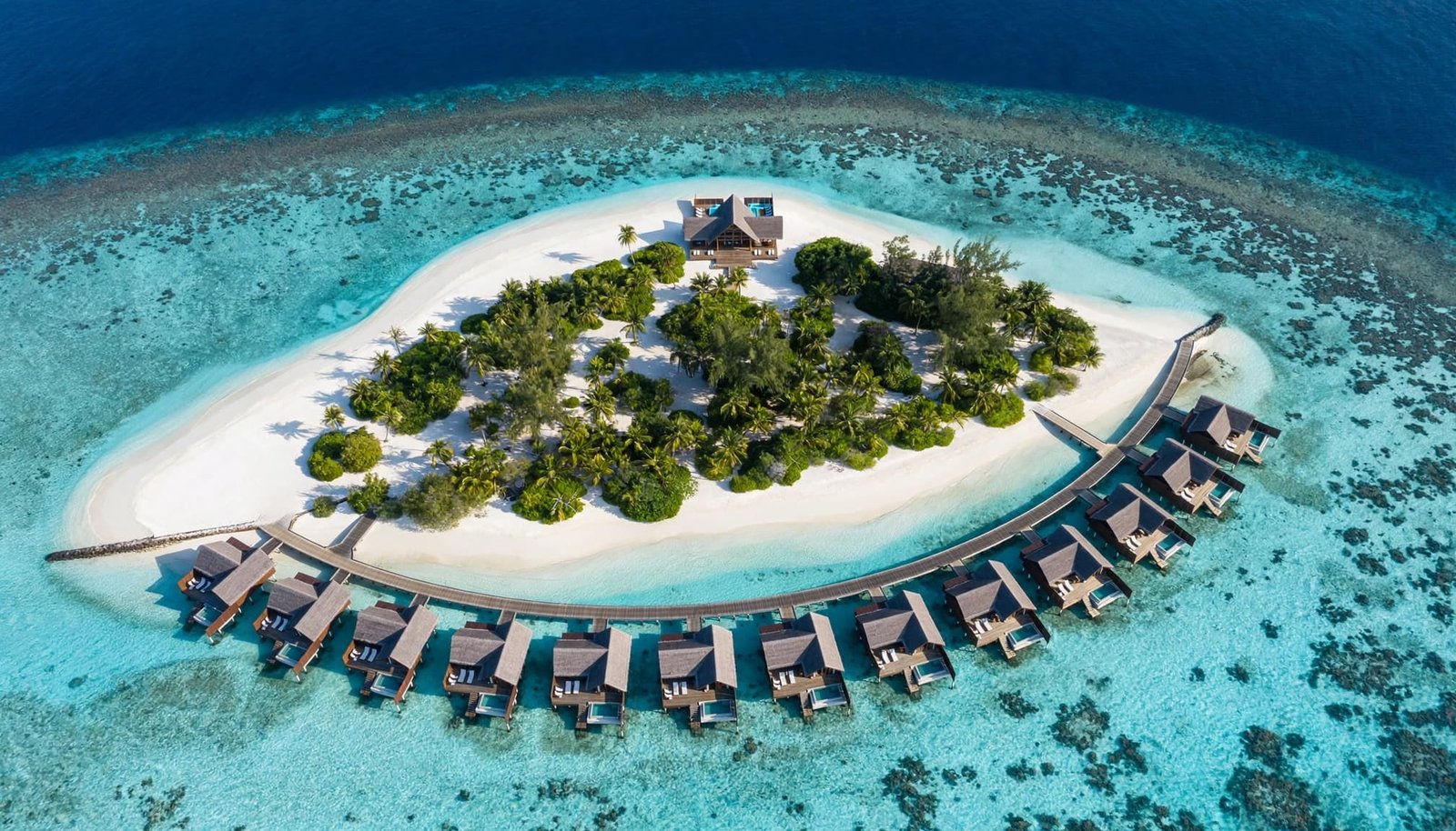 Aerial view of a private island resort with overwater villas and a white sand beach.